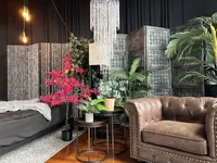 the corner in elevation boudoir's studio that include a bed with multiple sheet color options, a chich crystal chandelier and a leather club chair perfect for posing on