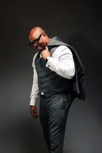 Male model smiling with sports coat over shoulder.