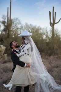 Destination Elopement non-traditional western groom picks bride up with mountain and dessert backdrop