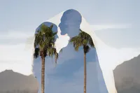Bride and groom silhouette double exposed non-traditional artistic portrait with palm trees under wedding veil