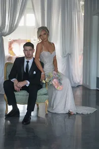 Bride and Groom posed on vintage chair from Annata Vintage co at Walnut Ridge Venue Traditional Wedding with Ella Floral Design Bouquet