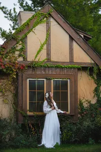 Iowa Cottage Inspired wedding venue with bridge standing against window and building with vines crawling up the side