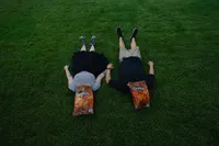 Iowa Non-traditioanl couple engagement session laying in grass with doritos bag over their faces
