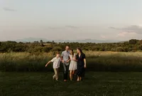 Family of four walking together in a field during a New England family photoshoot, enjoying a candid and outdoor shoot.