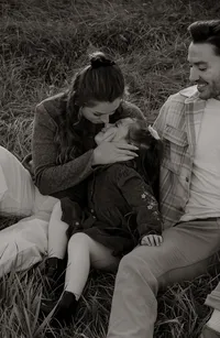 A sweet, candid moment of a mom giving her daughter a kiss on the nose while they cuddle in the grass. A warm, intimate family photography capturing genuine connection.