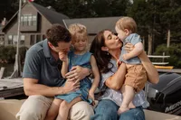 Family of four enjoying a summer boat photoshoot in Maine — mom, dad, daughter, and son laughing together, captured by New England family photography.