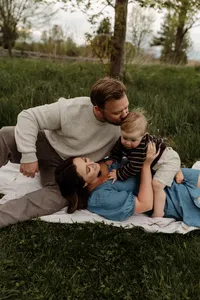 Couple with their baby boy lying together in the grass during a natural family photography session in New England.