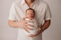 Newborn Photographer in Charleston -Father embraces his infant during Newborn Portrait Session in Charleston, SC.