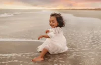 Charleston Baby Milestone Photographer - Toddler delights at the water on the beach during her Baby Milestone Portrait Session in Charleston, SC.