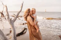 Folly Beach Maternity Photographer -- Pregnant woman poses for Maternity Photos at the Lighthouse Inlet Heritage Preserve on Folly Beach with iconic views of the Morris Island Lighthouse in the distance.