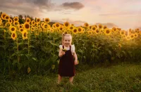 Charleston Baby Milestone Photographer - toddler stands in a field of sunflowers during Baby Milestone Portraits in Charleston, SC.