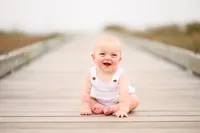 Charleston Baby Milestone Photographer - Baby laughs on a board walk by the beach in Isle of Palms during his Baby Milestone Portrait Session in Charleston.