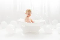 Baby plays in a splash bath during his first birthday Cake Smash Photoshoot at Holy City Babies Portrait Studio in Charleston, SC.