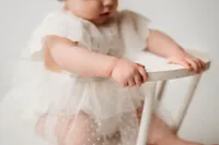 Charleston Cake Smash Photographer- Baby looks into the camera during Milestone Portraits at Holy City Babies Portrait Studio in Charleston, SC.