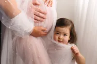 Toddler peers at the camera during her mother's Studio Maternity Photoshoot in Charleston, SC