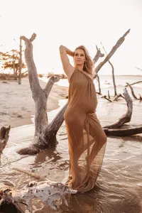Folly Beach Maternity Photographer -- Pregnant woman poses for Maternity Photos at the Lighthouse Inlet Heritage Preserve on Folly Beach with iconic views of the Morris Island Lighthouse in the distance.