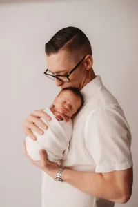 Newborn Photographer in Charleston -Father embraces his infant during Newborn Portrait Session in Charleston, SC.