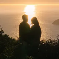 golden hour cliffside in san francisco couple on cliffside standing in sunlight by ocean