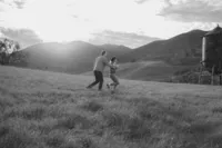 couple playing tag engagement photos in open field by water tower and mountain in bay area california