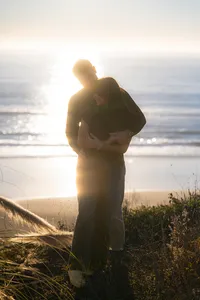 couple embracing in sunset ocean sparkle on cliffside in santa cruz