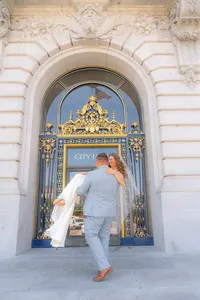 groom carries bride in front of san francisco city hall wedding