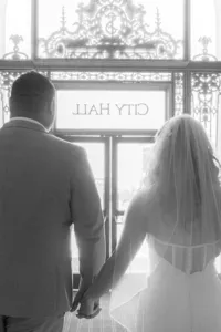 bride and groom exit under sign at san francisco city hall wedding