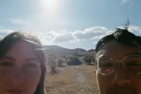 Bride and groom peeking into the camera in the desert.