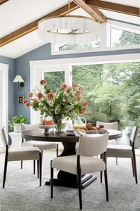 Sophisticated dining room designed by Glass House Design Group in Boston. Cream and wood chairs with dark table and a huge flower bouquet in front of bay windows. Effortlessly chic New England interior design that works for real life.