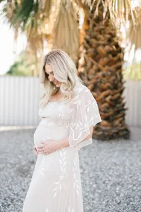 Pregnant woman in lace dress during outdoor maternity photo session by by Suzanne Karp Photography