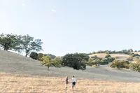 Documentary-style family image of them running in a grass field at a golden hour by Suzanne Karp Photography in Sausalito California