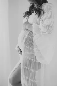 Black and white photo of pregnant woman in white maternity dress by Suzanne Karp Photography