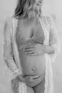 Black and white photo of pregnant woman during maternity portrait session in lace undergarments by Suzanne Karp Photography
