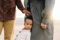 Natural light image of a son between her parents torso at the golden hour by Suzanne Karp Photography in Marin County California