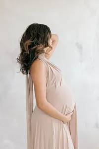 Pregnant woman in cream dress with hair and makeup during studio maternity portrait session by by Suzanne Karp Photography