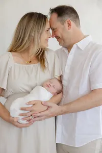 Photo of mom holding a newborn and touchin foreheads with dad while he has a hand on the newborn by Suzanne Karp Photography in Northern California