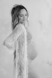 Black and white photo of pregnant woman during maternity portrait session in lace undergarments by by Suzanne Karp Photography