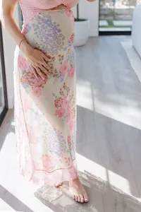 At-home maternity photo session of woman's belly in pink floral dress by Suzanne Karp Photography