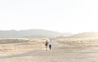 Couple holding hand and running outside with the mountains on the background.by Suzanne Karp Photography in Northern California