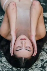 Woman reclining with her eyes closed and hands beside her face during a natural boudoir portrait.