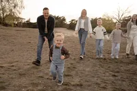 Kleine jongen rent voor z'n familie uit tijdens een familieshoot op de veluwe