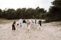 Kinderen rennen voor de volwassenen langs terwijl de volwassenen lopen over het zand tijdens een familiefotoshoot