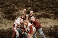 Familie staan allemaal dicht bij elkaar en ieder lacht breed tijdens een fotoshoot met familie