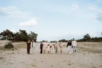 Familie loopt over een groot zandvlakte en kijken naar opa en oma tijdens een familieshoot