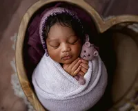 an award winning photograph taken of an african american baby holding a small teddy bear