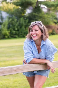 Heidi Peterson Photography leaning on fence rail with sunglasses and smile