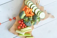 Fresh vegetable board with broccoli, carrots, celery, cucumber, and tomatoes, a fertility-friendly snack before pregnancy