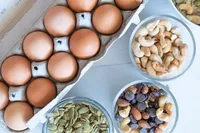 Protein sources flat lay of brown eggs, cashews, pumpkin seeds, and trail mix to support women on the path to pregnancy
