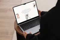 Woman holding a laptop showing a light and airy Showit website design