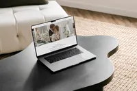 Laptop on a dark coffee table showing an elegant Showit template for photographers