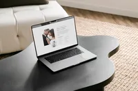 Laptop on a dark coffee table showing a light and airy showit website template for photographers
